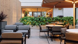 An outdoor seating area with tables and chairs, surrounded by plants and a wooden wall. - Altis Porto Hotel, member of Preferred Hotels & Resorts – L.V.X. (Porto)