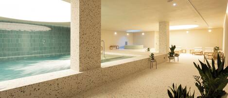 Un área de spa con una piscina grande, zonas de descanso y plantas en macetas.
