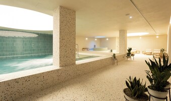 Et spa-område med en stor swimmingpool, siddepladser og plantekasser.