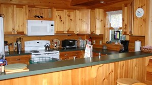 Eine Küchenzeile im Holzblockhaus-Stil mit Mikrowelle, Herd und verschiedenen Geräten.