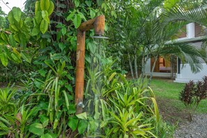 Une fontaine en bois, située dans un jardin luxuriant et agrémentée de diverses plantes tropicales.