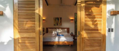 Un dormitorio con cama, ventilador de techo y una obra de arte en la pared.