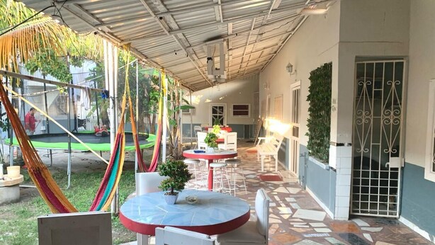 Een buitenpatio met ronde tafels en stoelen, een hangmat en een betegelde vloer.