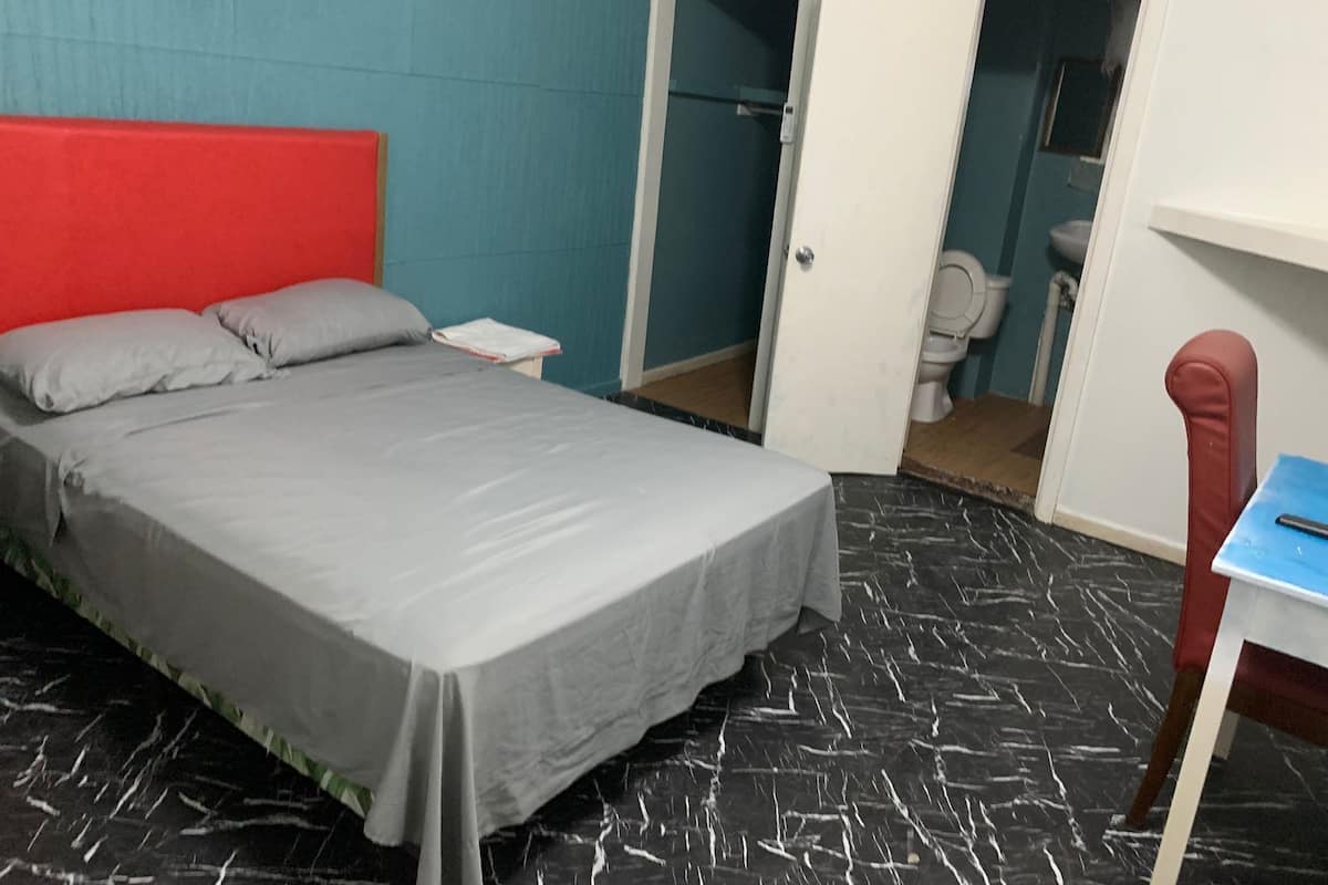 Een kamer met een bed, een bureau, een stoel en een toilet.