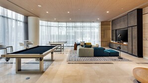 A modern living room with a pool table, comfortable seating, a flat-screen TV, and large windows. - Modern Condo 2bd/2bth, Best Brickell Location (Miami)