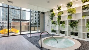 A modern indoor pool area with a hot tub, surrounded by glass walls and a plant wall. - Modern Condo 2bd/2bth, Best Brickell Location (Miami)