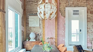 A dining area with a long wooden table, orange upholstered chairs, a hanging light fixture, and a brick wall. - 3E Sunrise View (Honey Grove)