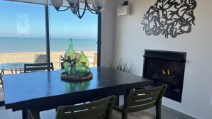 Ein Essbereich mit Blick auf den Strand, inklusive Kamin und dekorativer Vasen auf dem Tisch.