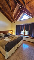 Un dormitorio con una cama grande, tragaluz y vistas al exterior.
