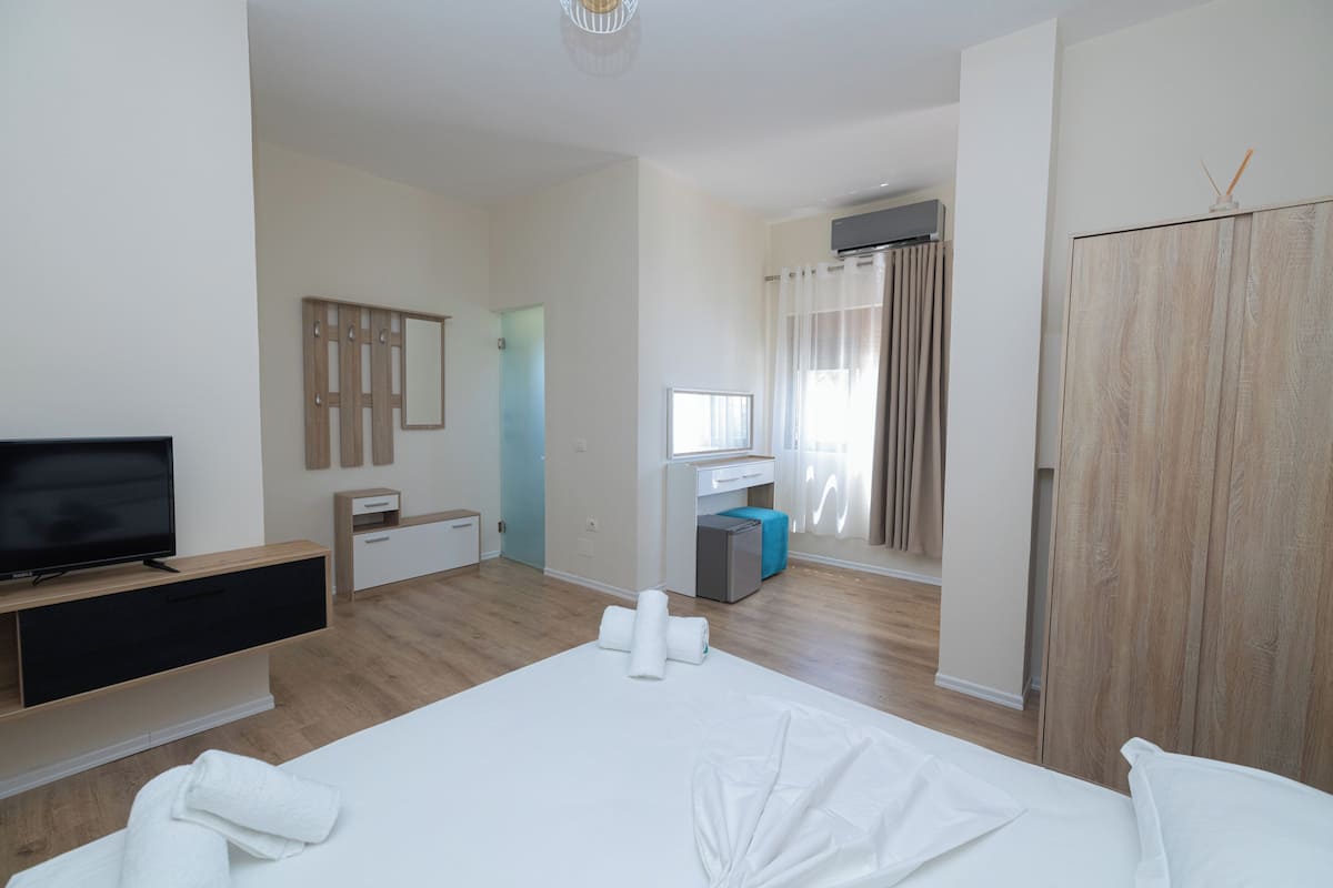 A hotel room with a bed, a TV, a desk, and a wardrobe.