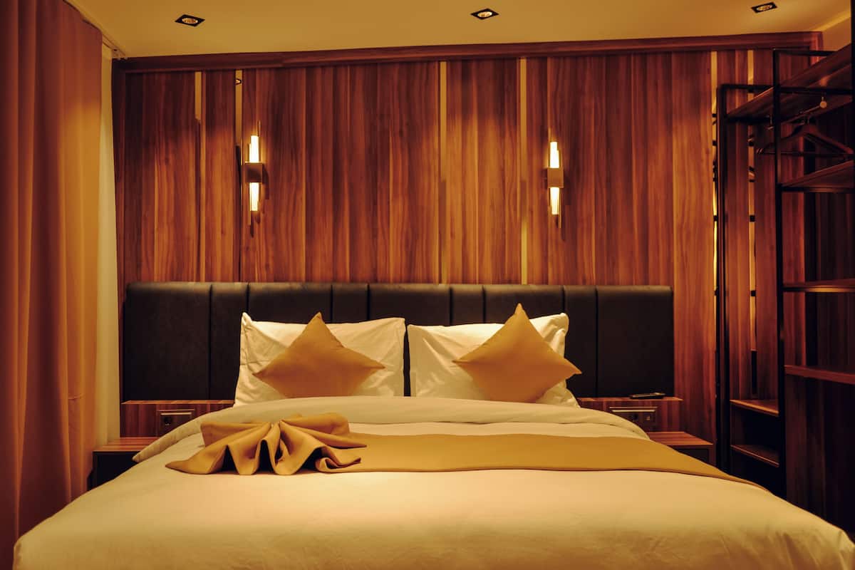 Une chambre d’hôtel avec un grand lit, des boiseries et deux lampes de chevet.