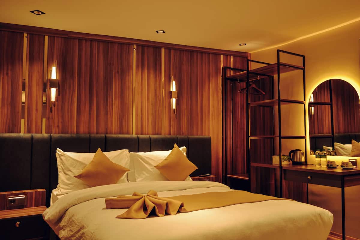 Une chambre d’hôtel avec un grand lit, des lambris en bois aux murs, un bureau avec un miroir et une table de chevet.