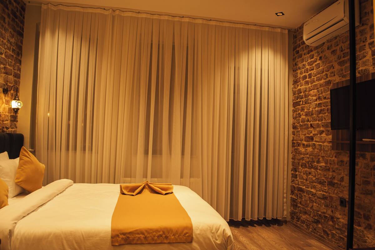 Une chambre d’hôtel avec un grand lit, un mur en briques et un téléviseur fixé au mur.