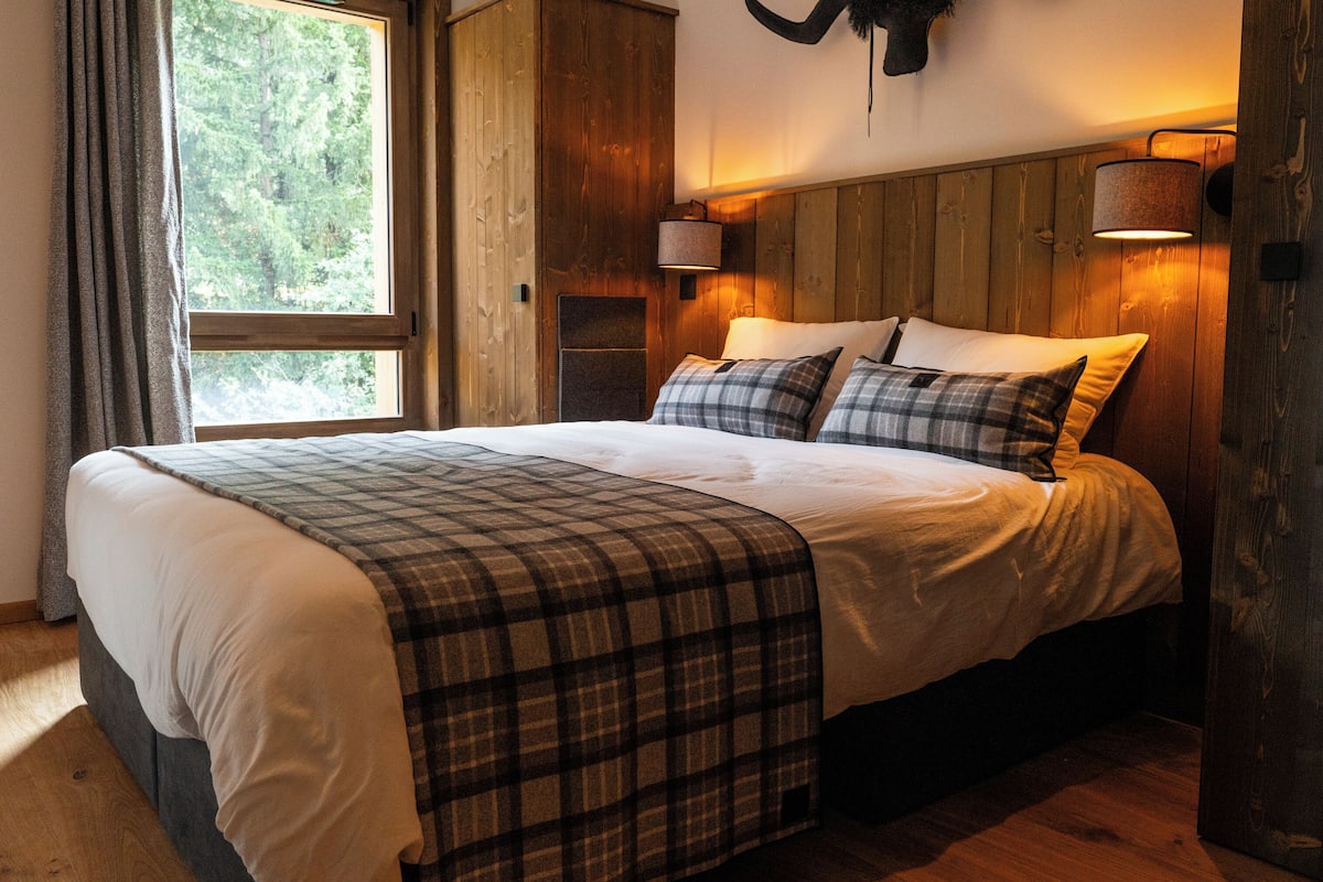 Ein Schlafzimmer mit einem großen Bett, einem Holzkopfende und einem Fenster mit Vorhängen.