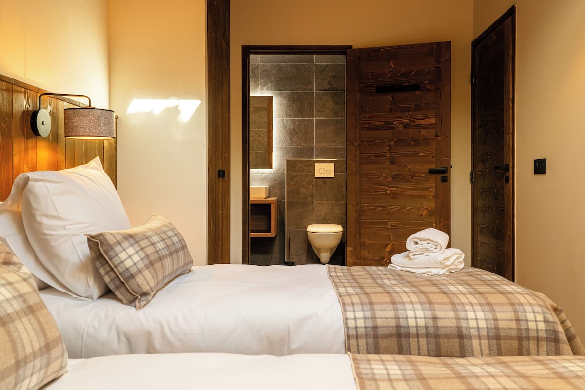 Ein Hotelzimmer mit einem Bett, einem Nachttisch, einer Lampe und einer Holztür.