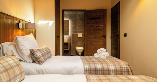Una habitación de hotel con una cama, una mesita de noche, una lámpara y una puerta de madera.