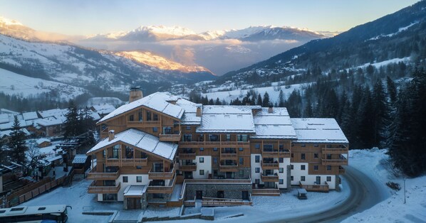 Un gran lodge de varios pisos con techo nevado, rodeado de un paisaje montañoso.