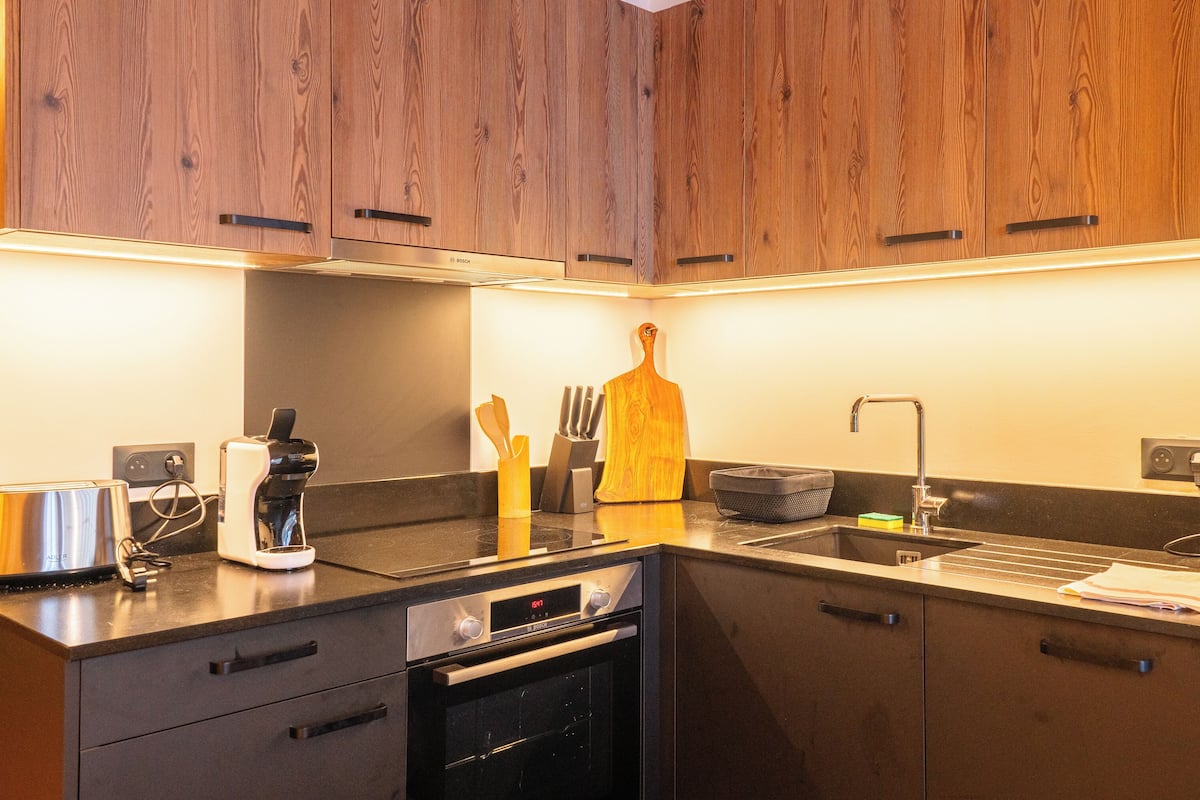 Eine moderne Küche mit Holzausstattung, einem Einbauofen, einem Spülbecken und einem Toaster.