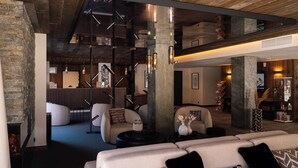 A modern interior with a stone wall, seating area, and a staircase. - Résidence l’Ecrin d’Argent by My Mountain Resort (Les Avanchers-Valmorel)