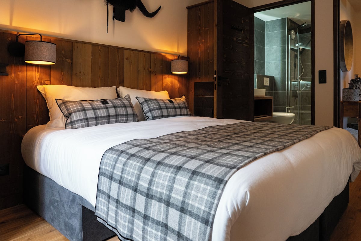 Ein modernes Schlafzimmer mit einem großen Bett, einem Holzkopfende und einer Duschkabine aus Glas.