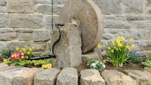 A stone wall with a water pump and flower beds. - 2 bedroom accommodation in Grinkle, near Staithes (Grinkle, near Staithes)