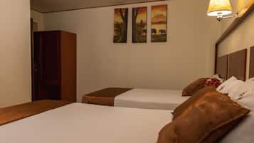 Una habitación de hotel con dos camas, un armario de madera y tres cuadros en la pared.