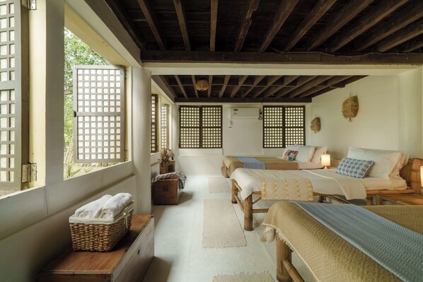Una tradizionale stanza in stile giapponese, con pavimento in tatami, soffitto basso con travi in legno e una porta scorrevole con motivo a griglia.