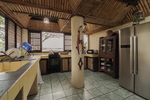 Una cocina con un amplio pilar central, un refrigerador, armarios y vistas a través de una ventana.