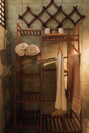 A metal towel rack with two towels, one rolled and one folded, and a brown towel hanging. - Serene beach front Villa near Vigan (San Juan)