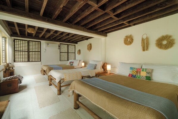 Une pièce de style traditionnel, avec des poutres en bois, des tatamis et un lit recouvert d’une courtepointe aux couleurs vives.