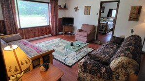 A living room with a sofa, armchair, wooden coffee table, and a television.