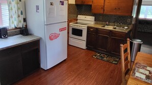 A compact kitchen with wooden cabinets, a white refrigerator, a stove, and a sink.
