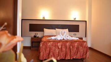 Una habitación de hotel con una cama grande, una mesita de noche y una lámpara fijada a la pared.