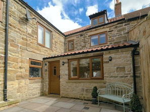 A stone building with a wooden door, windows, and a tiled roof.