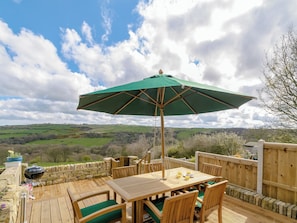 An outdoor patio with a table, chairs, and a grill.