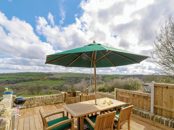 Un patio exterior con una mesa, sillas y una parrilla.