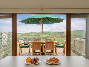A dining area with a table, chairs, and an umbrella, overlooking a scenic landscape.
