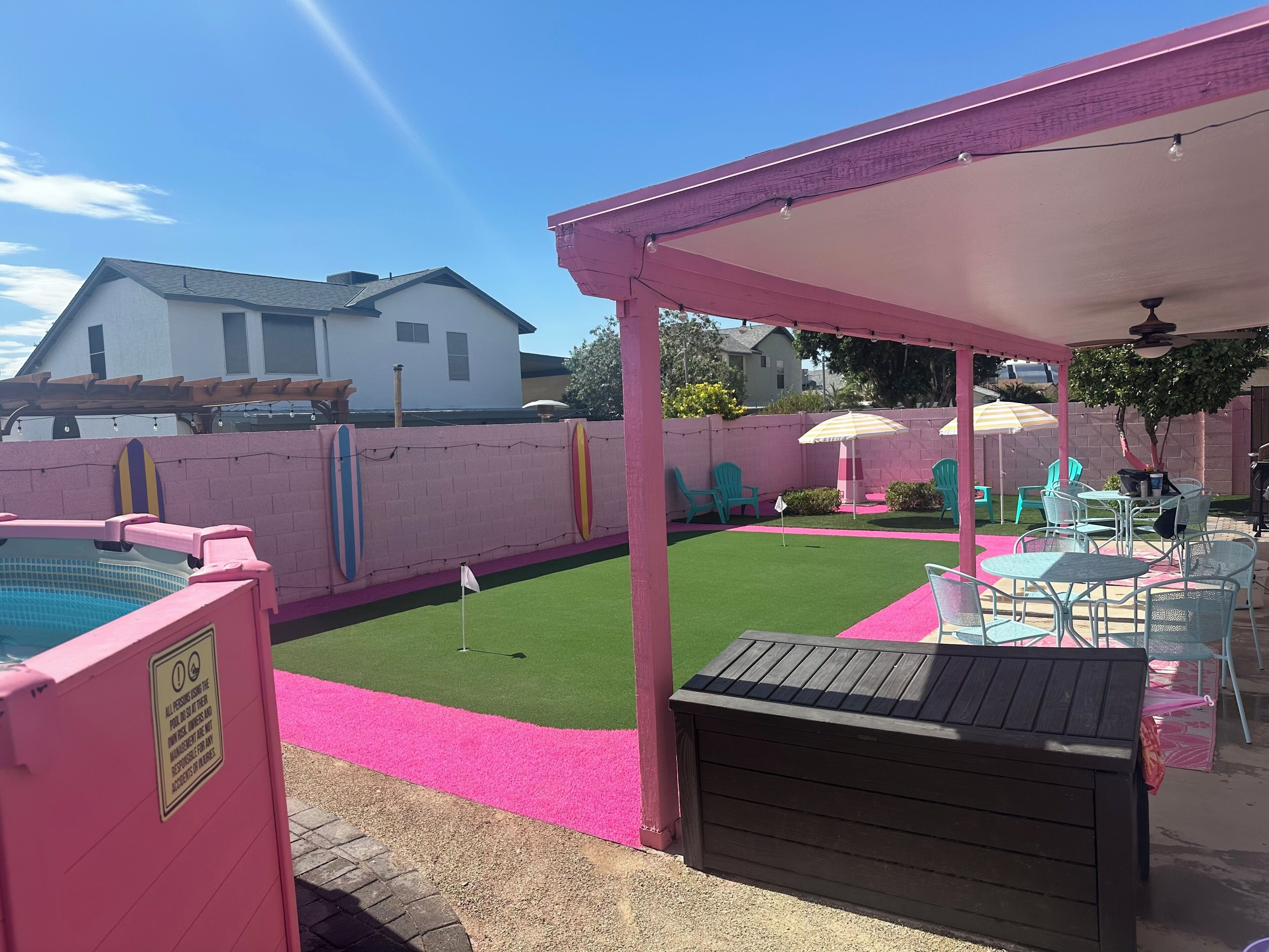 En baghave med swimmingpool, overdækket terrasse og en lille græsplæne.