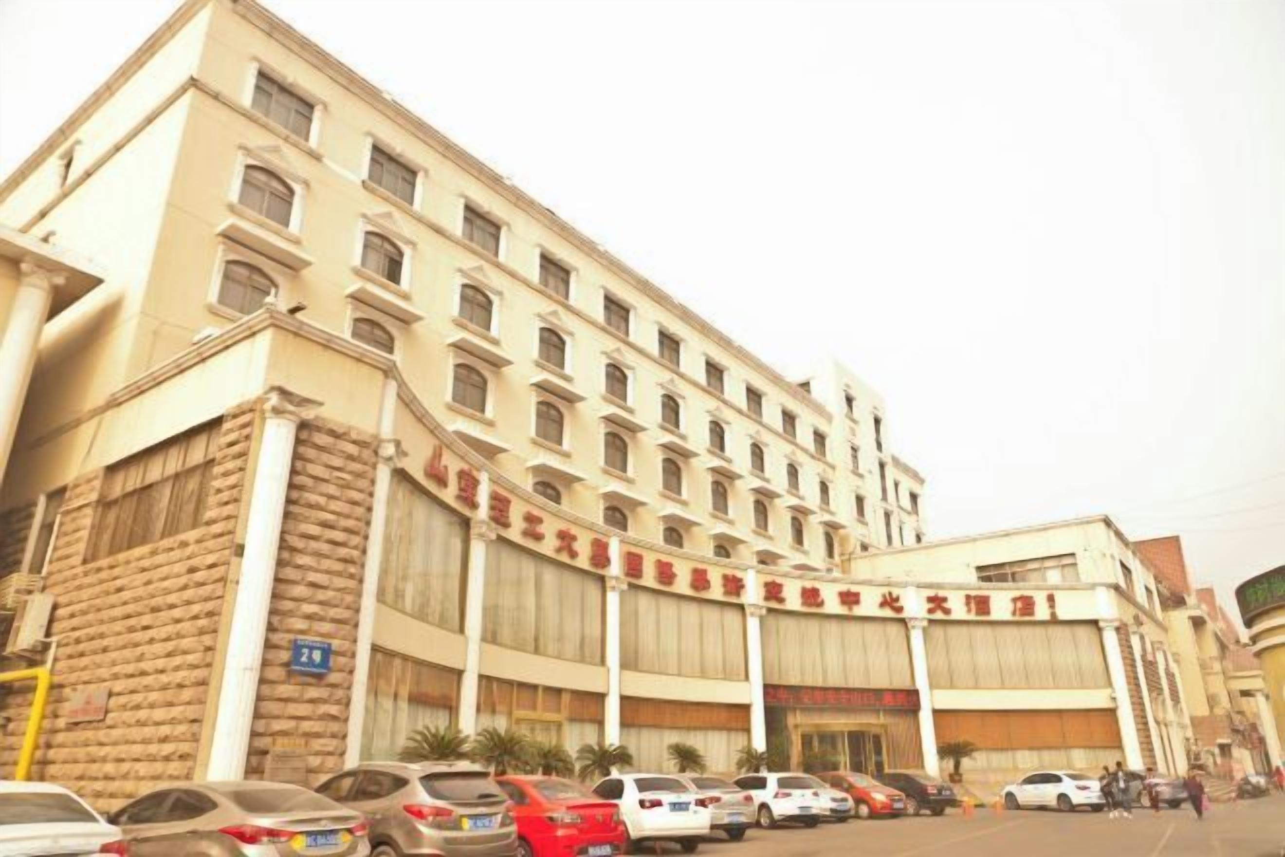 A multi-story hotel with a large parking lot in front.