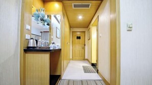 A narrow hallway with a wooden floor, a small kitchenette on the left, and a door at the end. - International Academic Exchange Center of Shandong University of Technology Hotel (Zibo)