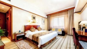 A hotel room with a bed, desk, chair, bedside table, lamp, and a window with curtains. - International Academic Exchange Center of Shandong University of Technology Hotel (Zibo)