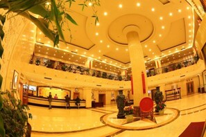 Un hall amplio con una columna central, una mesa de recepción y una zona de estar circular roja.