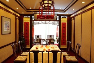 Comedor chino tradicional con una mesa dispuesta para una comida, sillas y un farol decorativo.