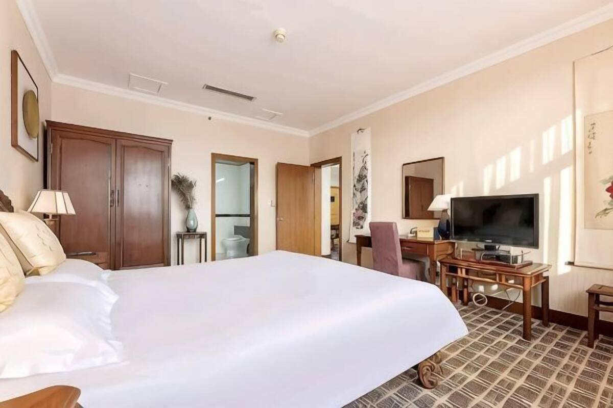 Een hotelkamer met een groot bed, een bureau met een televisie, een stoel en een kledingkast.