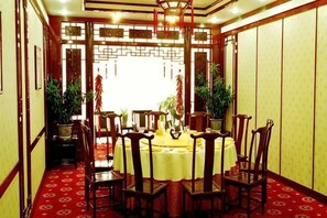 A traditional dining room with a round table, chairs, and potted plants. - International Academic Exchange Center of Shandong University of Technology Hotel (Zibo)