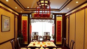 A traditional Chinese dining room with a long table set for a meal, surrounded by wooden chairs. - International Academic Exchange Center of Shandong University of Technology Hotel (Zibo)