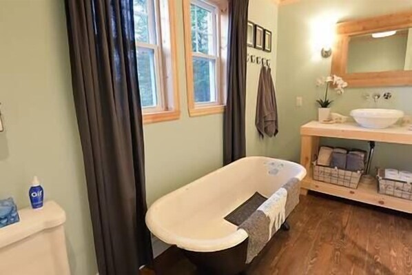 A bathroom with a bathtub, a sink, a mirror, and a window. - Charlevoix - Chalet Le DesBouleaux (Saint-Aimé-des-Lacs)