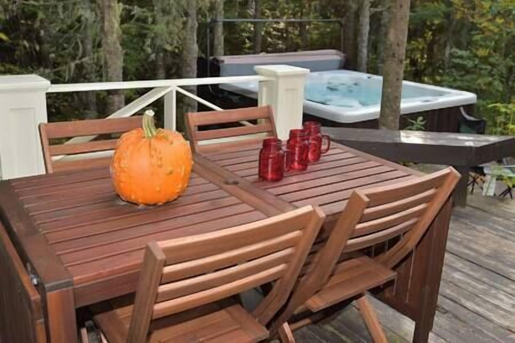 Eine Holzterrasse mit Tisch und Stühlen, einem Kürbis und roten Tassen.