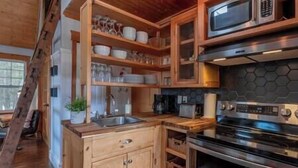A kitchen with wooden cabinets, a microwave, a stove, and a sink. - Charlevoix -  Chalet Le Cormier (Saint-Aimé-des-Lacs)