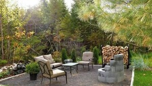 An outdoor patio area with a seating arrangement, a fire pit, and a stack of firewood. - Charlevoix -  Chalet Le Cormier (Saint-Aimé-des-Lacs)